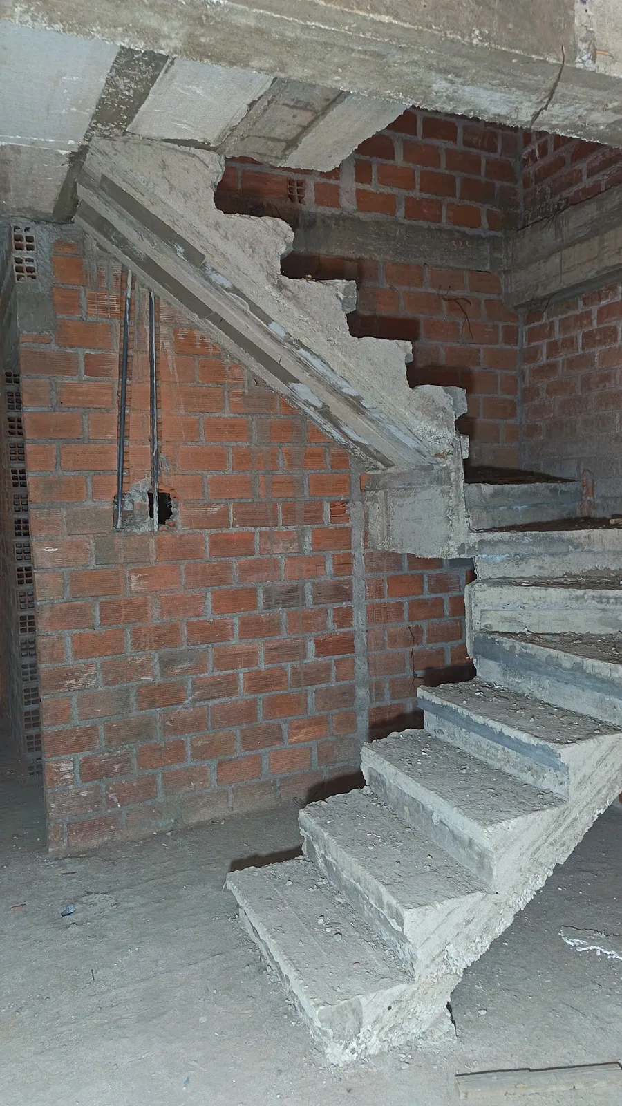 Escalera de concreto cuya llegada parece apoyarse sobre una vigueta en vez de un apoyo claramente resuelto por diseño