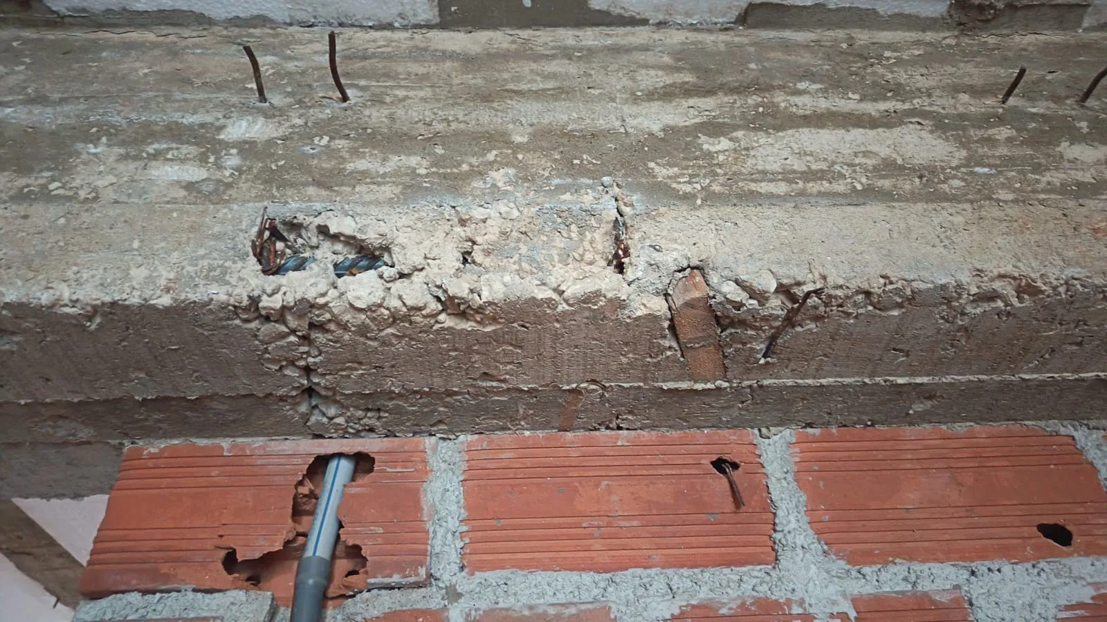 Viga con cangrejeras, acero visible, taco de madera como separador y muro de ladrillo tubular mal ejecutado